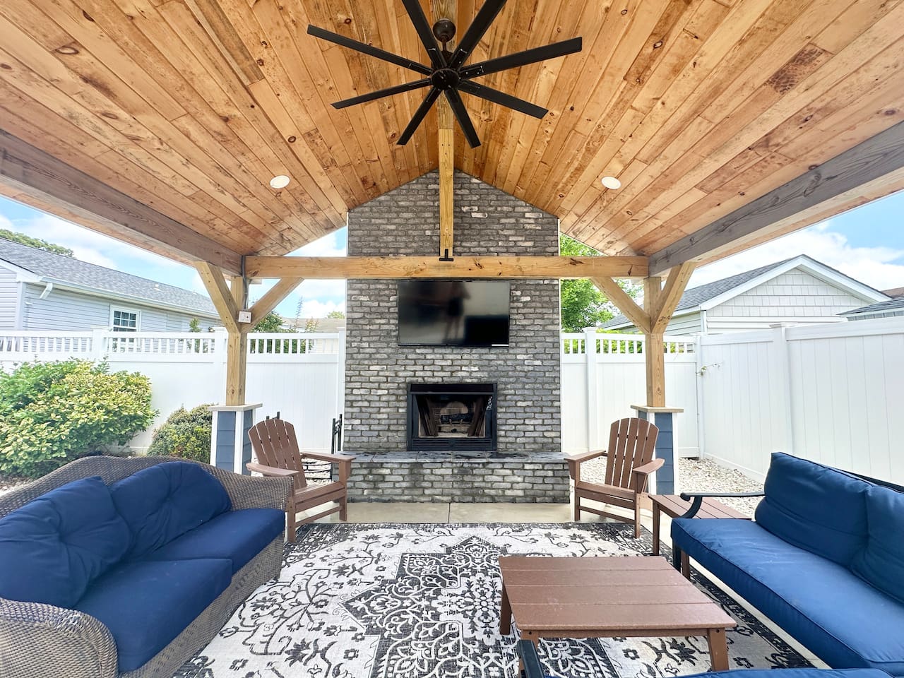 Unwind in luxury under this vaulted wood ceiling. The covered lounge features a grand stone fireplace and outdoor TV, offering a cozy, stylish escape for your next vacation.