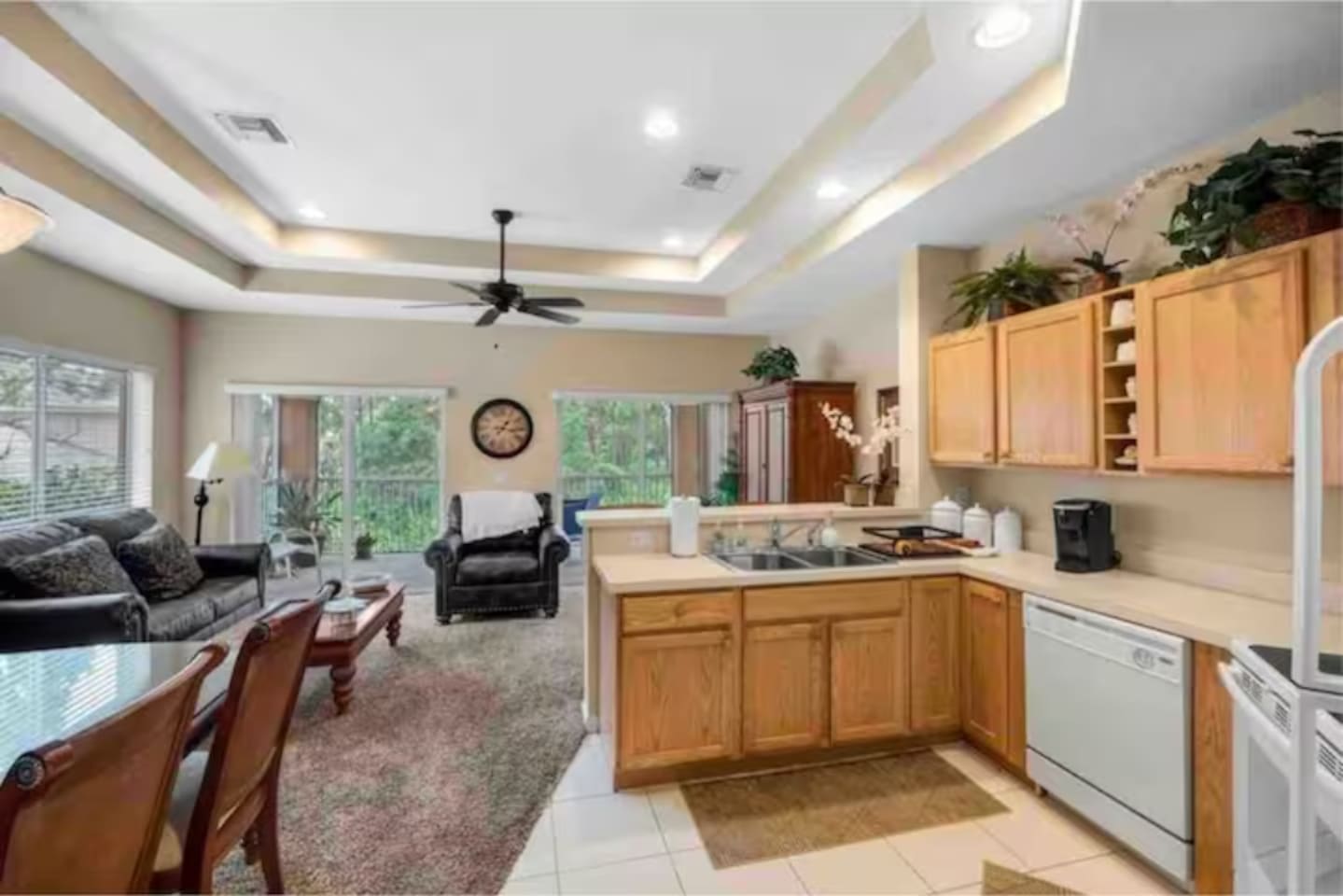 Open kitchen and living area featuring tray ceilings, full-size appliances, breakfast bar seating, and plenty of natural light.