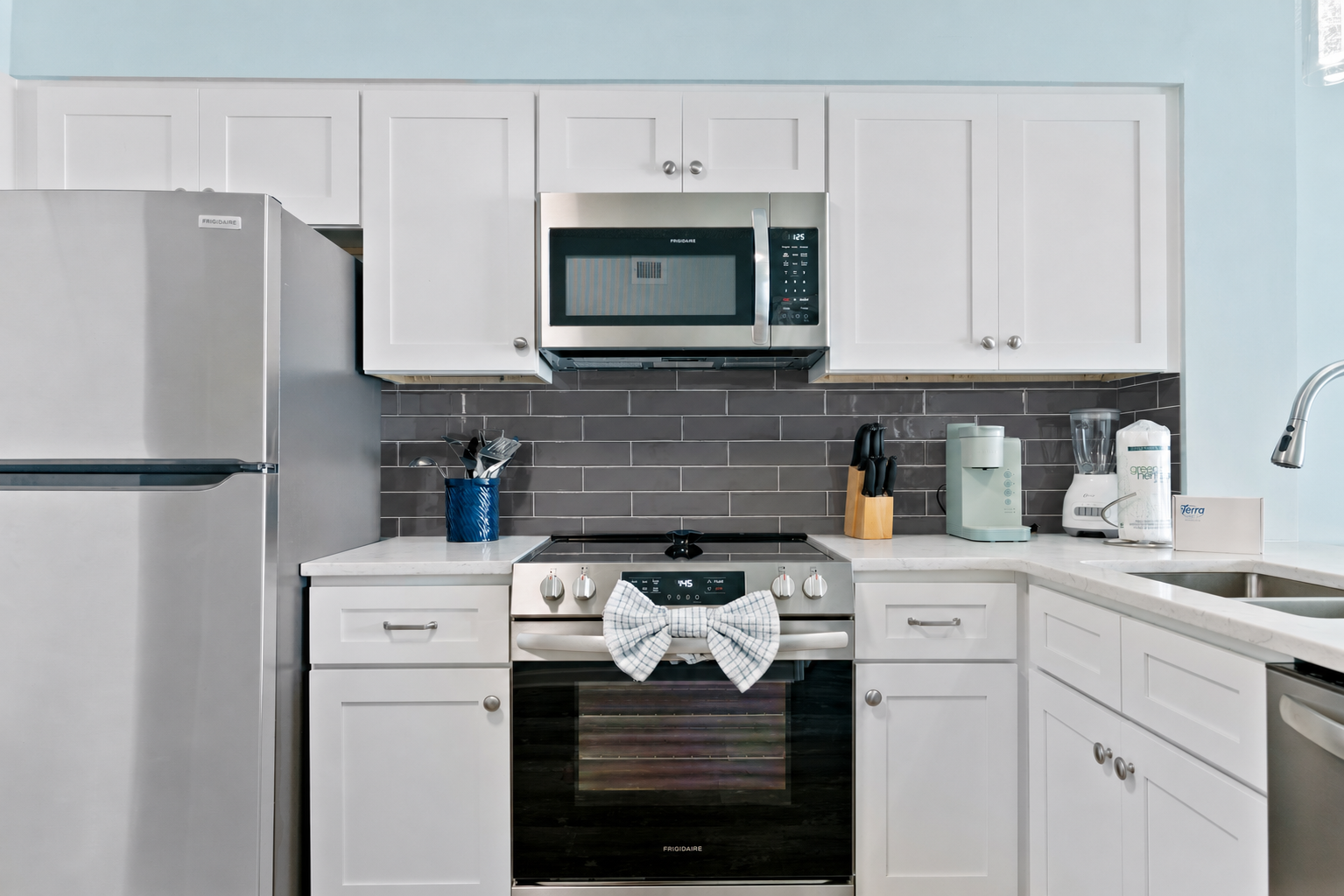 A modern kitchen featuring a sleek silver fridge, countertop stove with oven,dishwasher, microwave, and state-of-the-art appliances—fully equipped with everything you need for effortless cooking and dining.