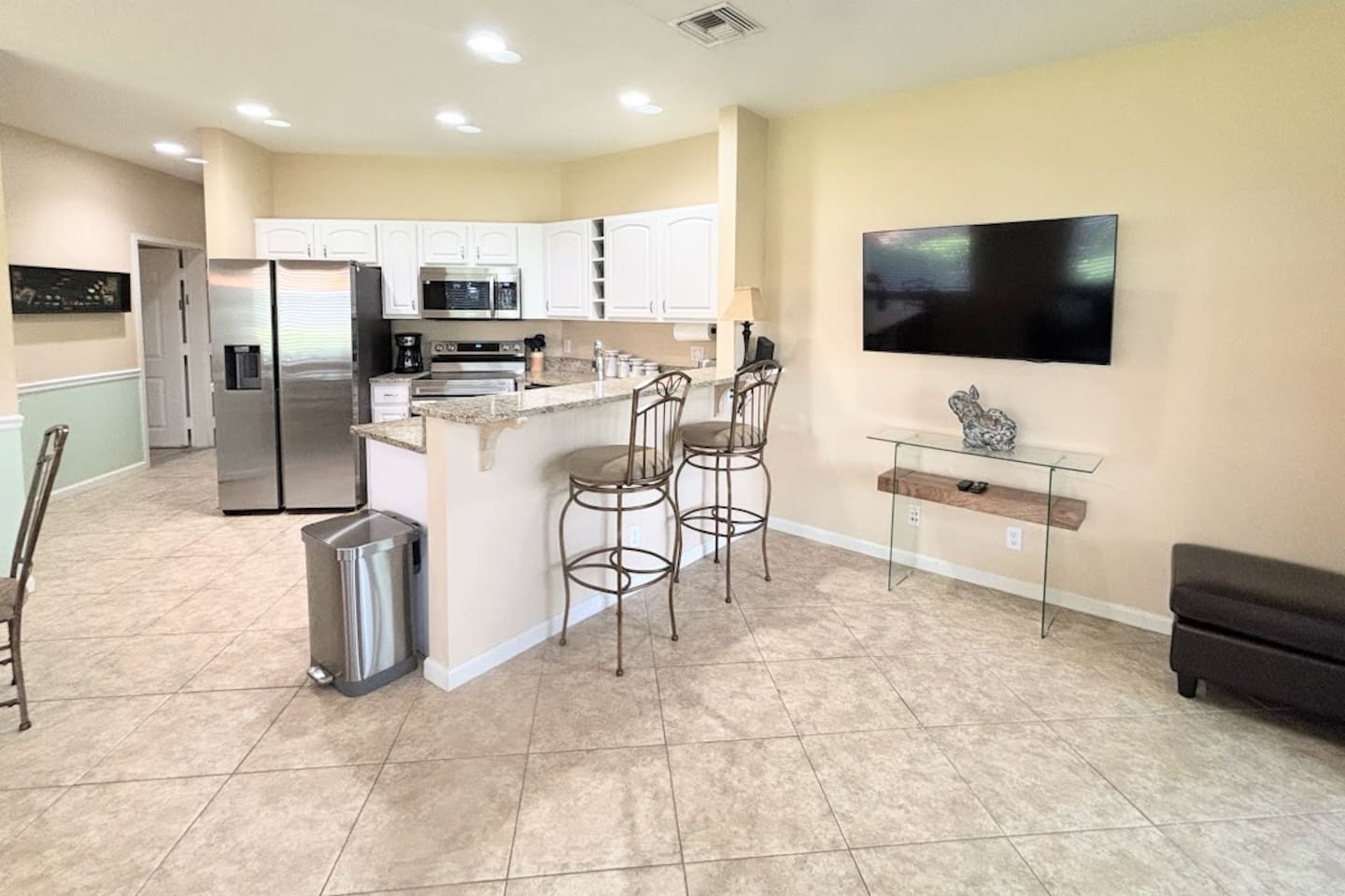 Open kitchen and living area featuring breakfast bar seating, large TV, and a clean, comfortable layout.