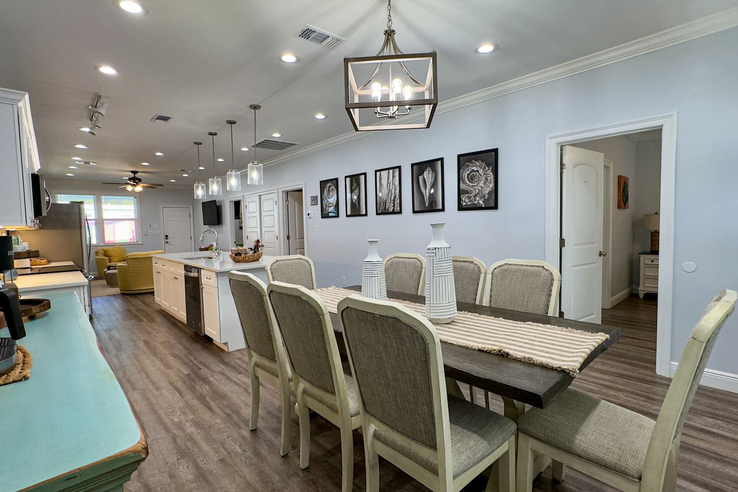 Open-concept kitchen and dining area with a long farmhouse table, modern lighting, and plenty of space for group meals.