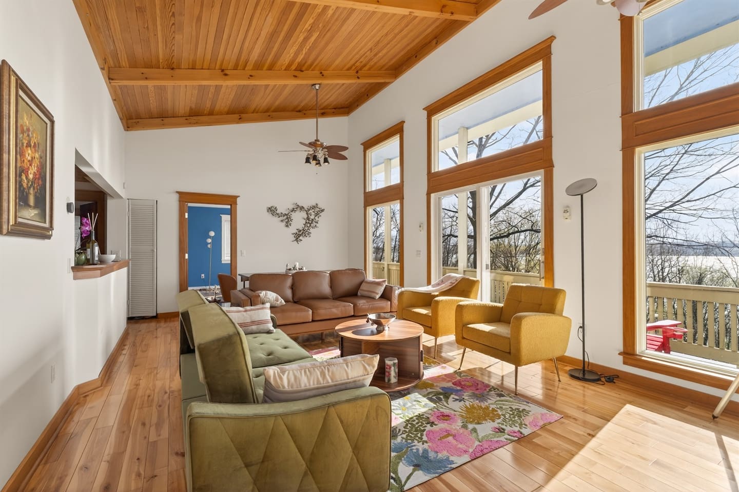 Bright and open living room with soaring ceilings, floor-to-ceiling windows, and stunning Canandaigua Lake views—relax in natural light, enjoy cozy seating, and unwind while taking in peaceful nature from the comfort of home