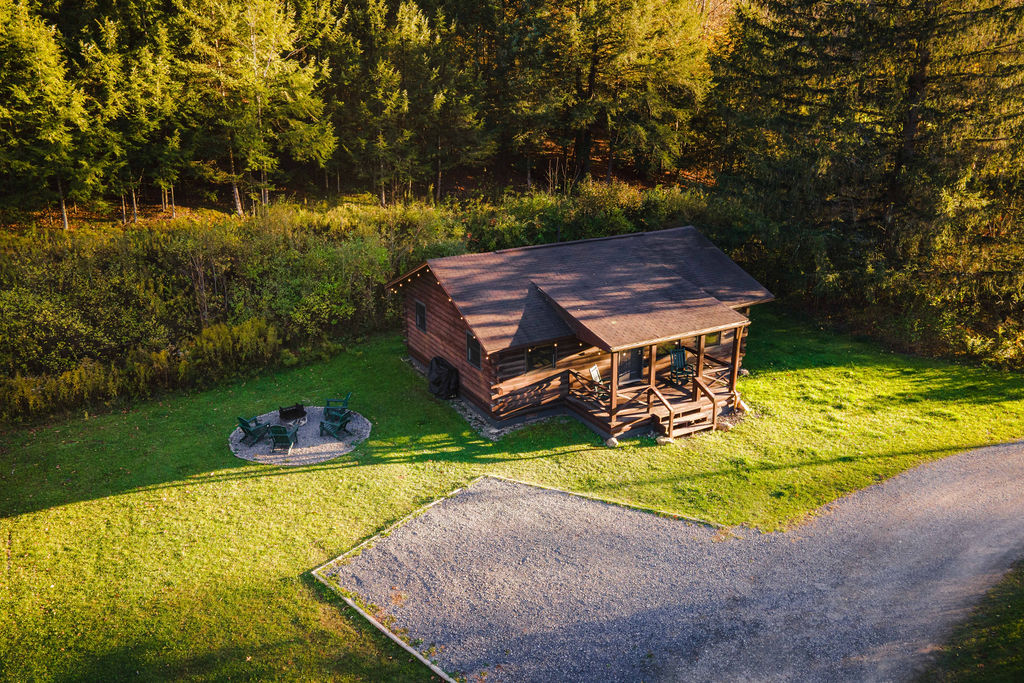 Private cabin with fire pit seating, tucked against the trees — a peaceful spot to relax day or night.