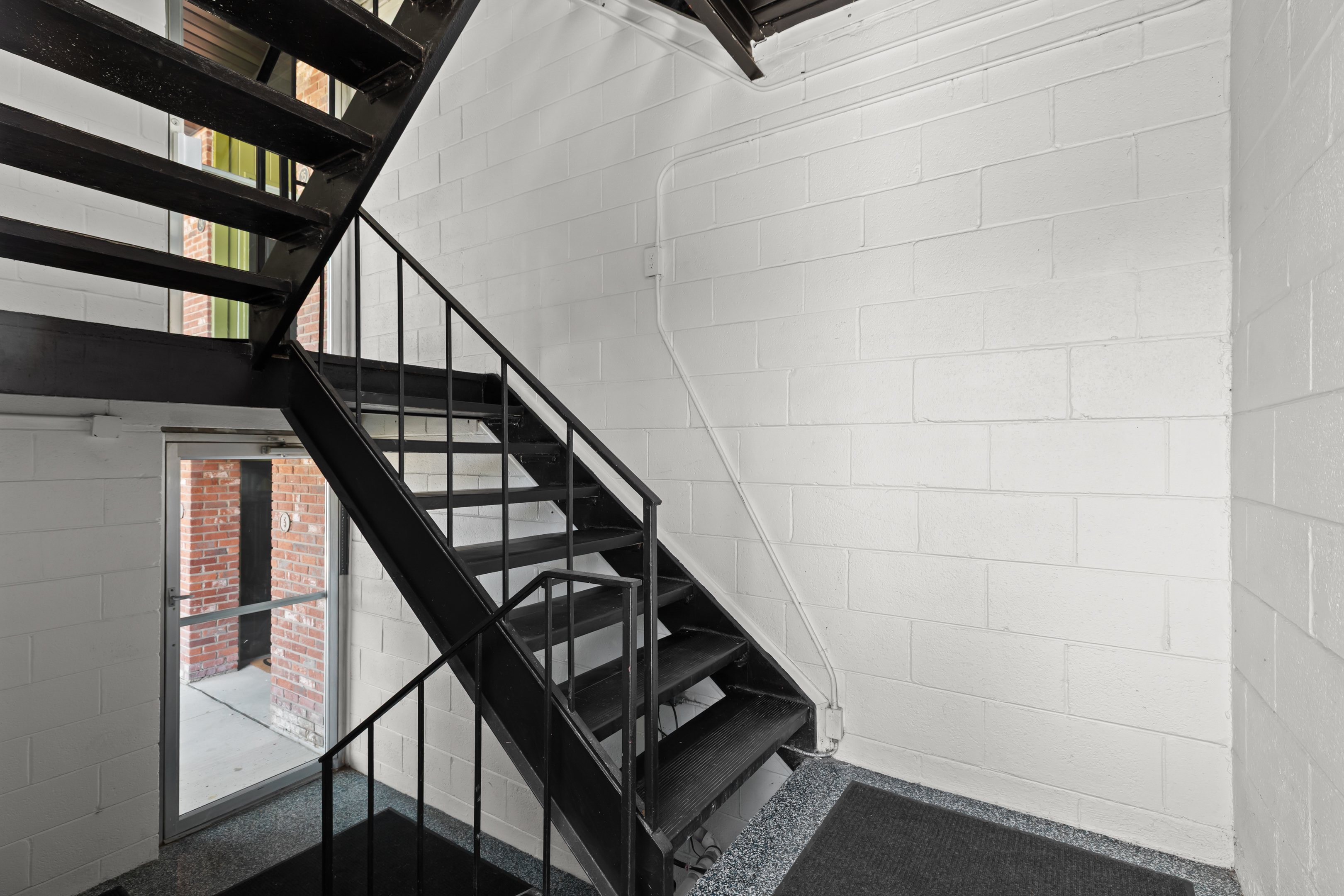 Clean, modern staircase with black metal design and bright white walls