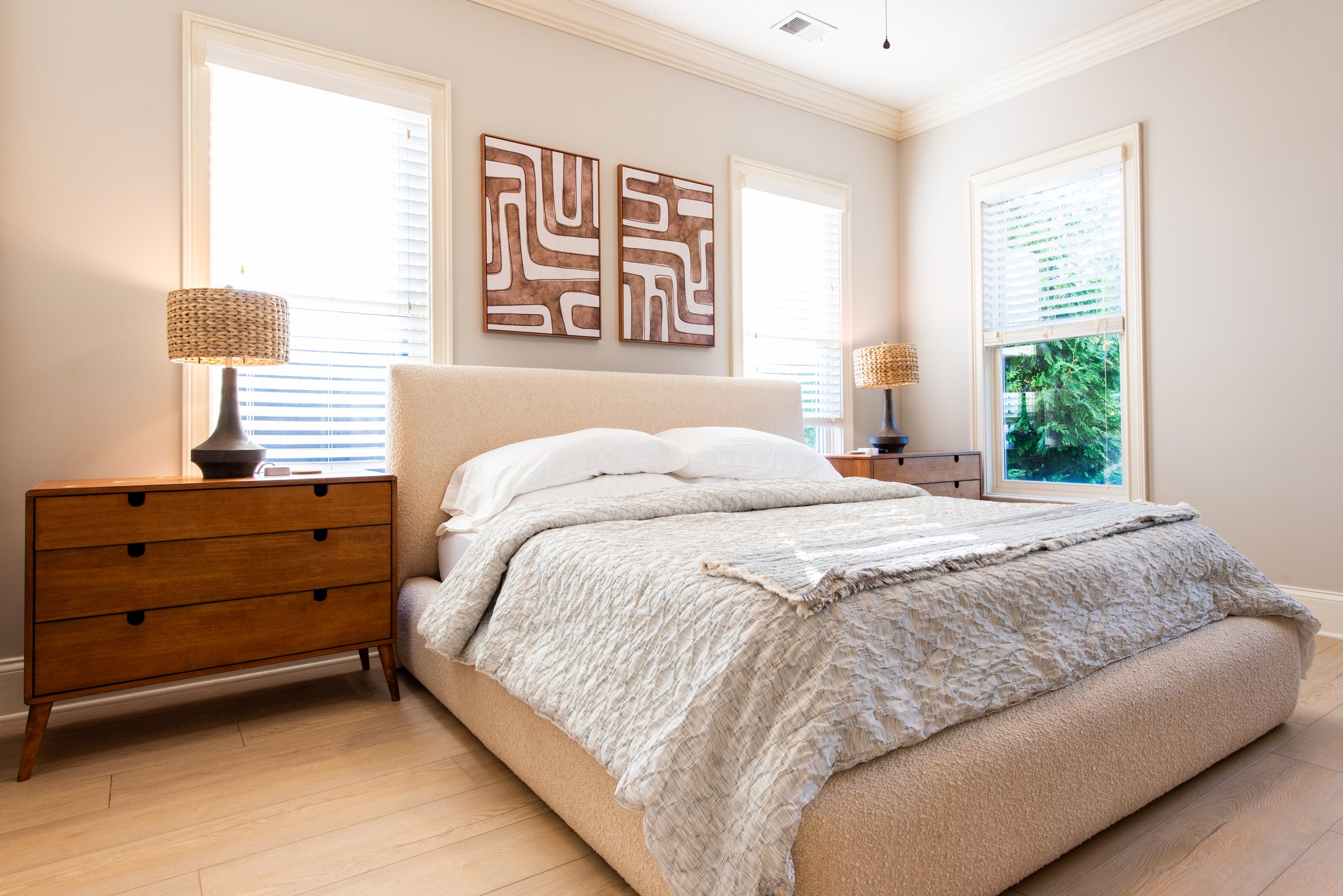 Wake up to natural light in the spacious primary bedroom, with matching nightstands and reading lamps.