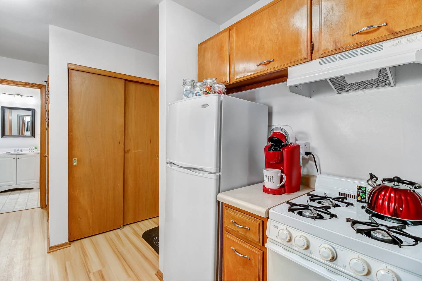 Assorted teas, sugar, creamer and coffee in jars on top of fridge.