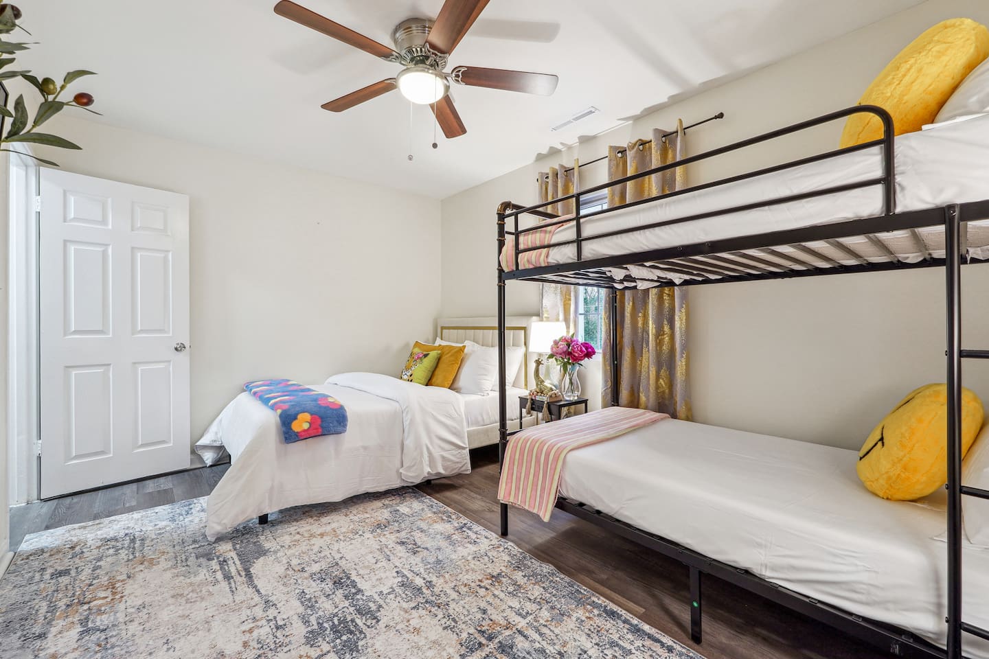 A cozy bedroom featuring a double bed, a bunk bed, a window, a bedside shelf with a lamp, and a TV — perfect for families or groups to relax and unwind.
