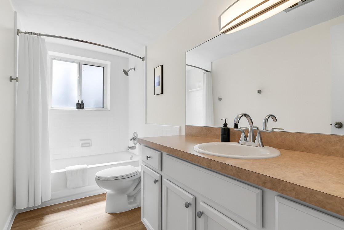 Freshly updated bathroom with granite vanity, stylish fixtures, and full-length mirror.