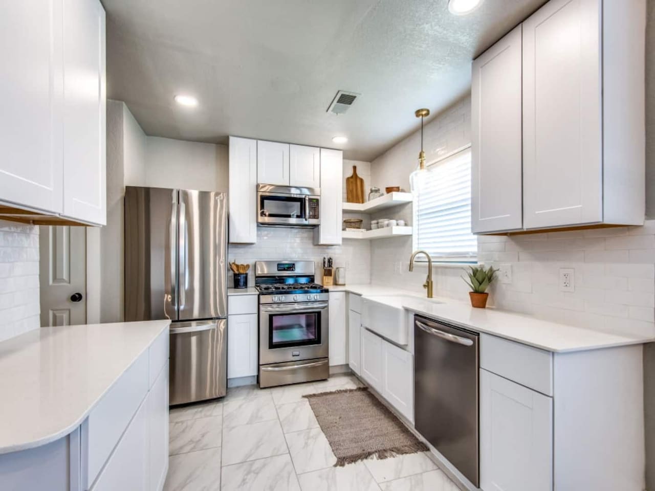 Renovated kitchen with stainless steel appliances, white shaker cabinets, and quartz countertops. Stocked with Keurig, blender, cookware, and dishes. Modern farmhouse Airbnb in Aubrey TX near Frisco, Denton, and wedding venues.