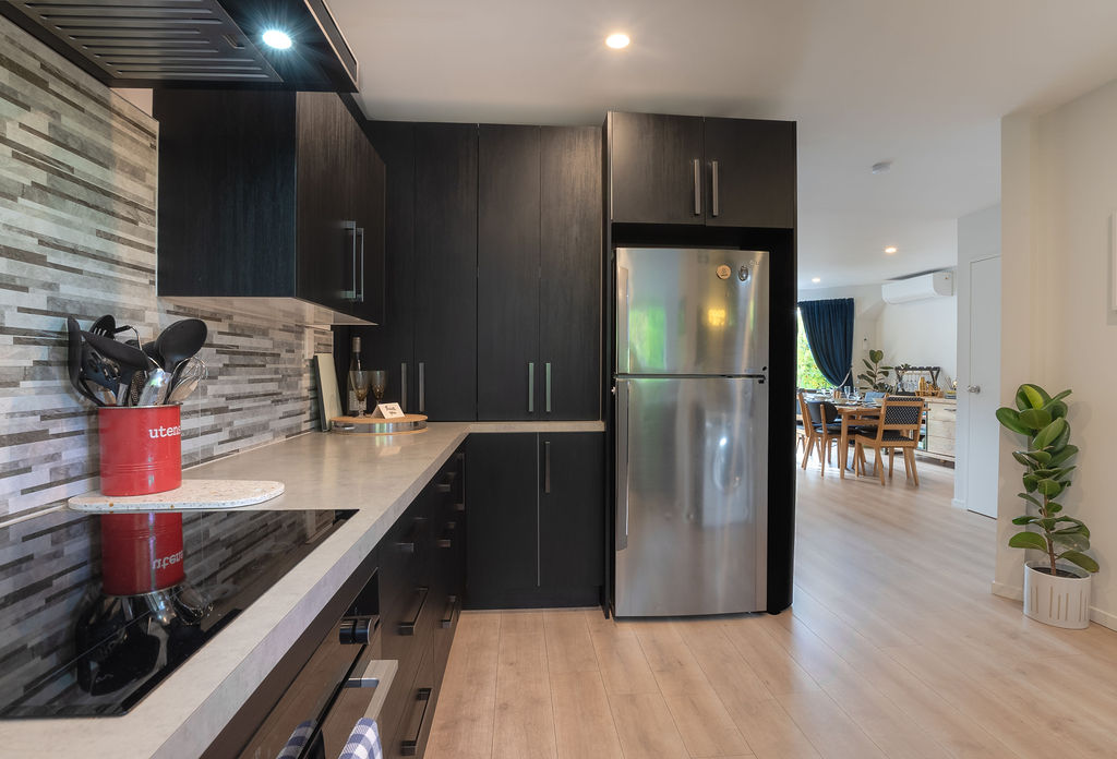 Dark cabinetry, full-size appliances and the open view through to the dining area give this kitchen a polished, practical feel.