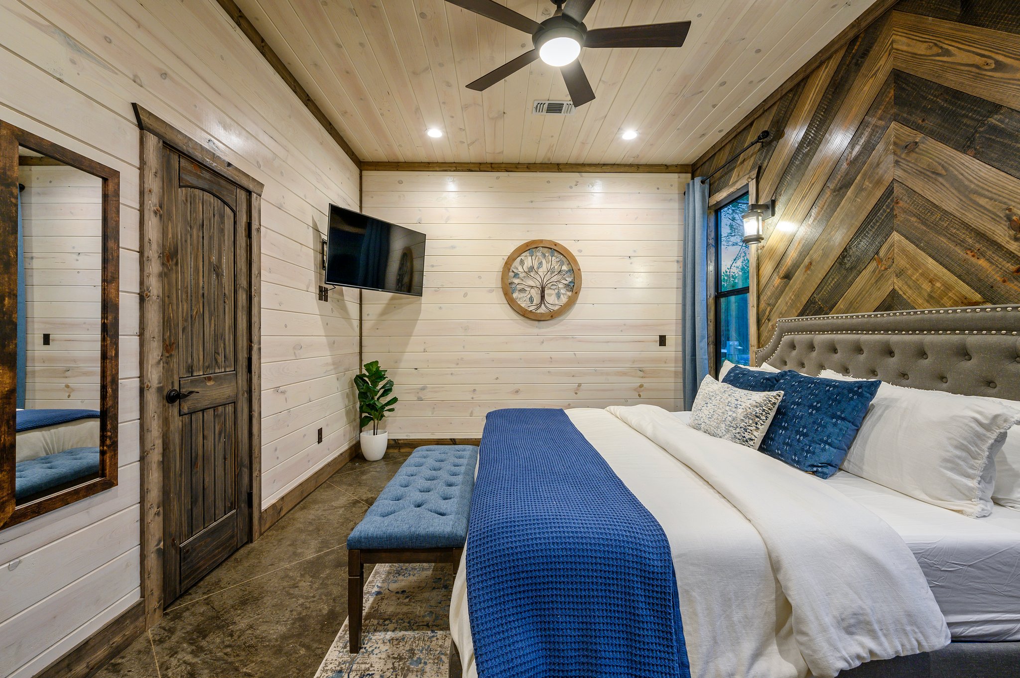 Boutique comfort meets cabin charm in this light-filled master bedroom.