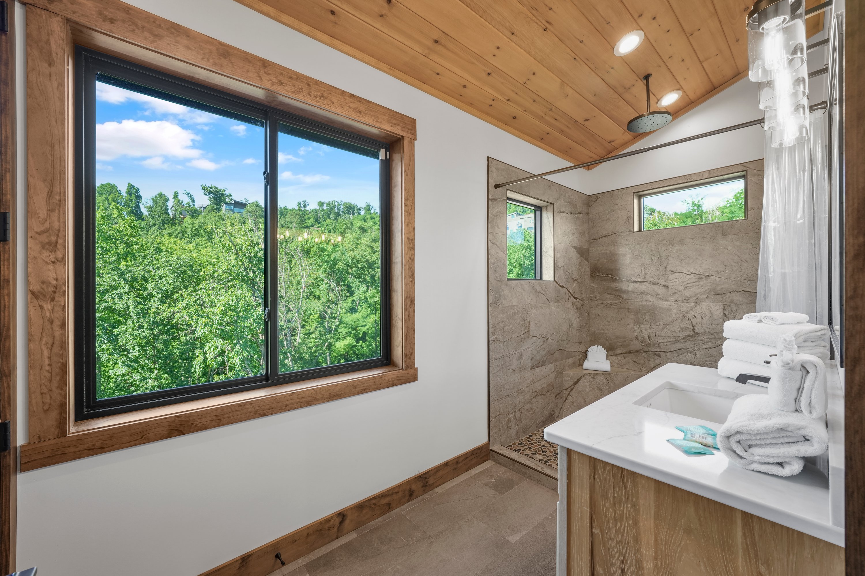 King Suite with vaulted ceilings an x-large TV. Unwind in the en-suite bathroom featuring a luxurious walk-in shower with a natural river rock floor, bringing  the Smoky Mountains indoors for a spa retreat.