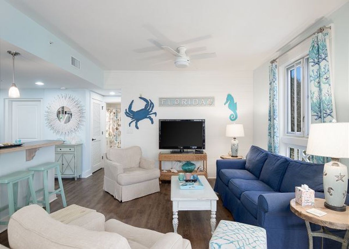 Living room with HDTV, blue sleeper sofa and armchairs, open to the kitchen breakfast bar