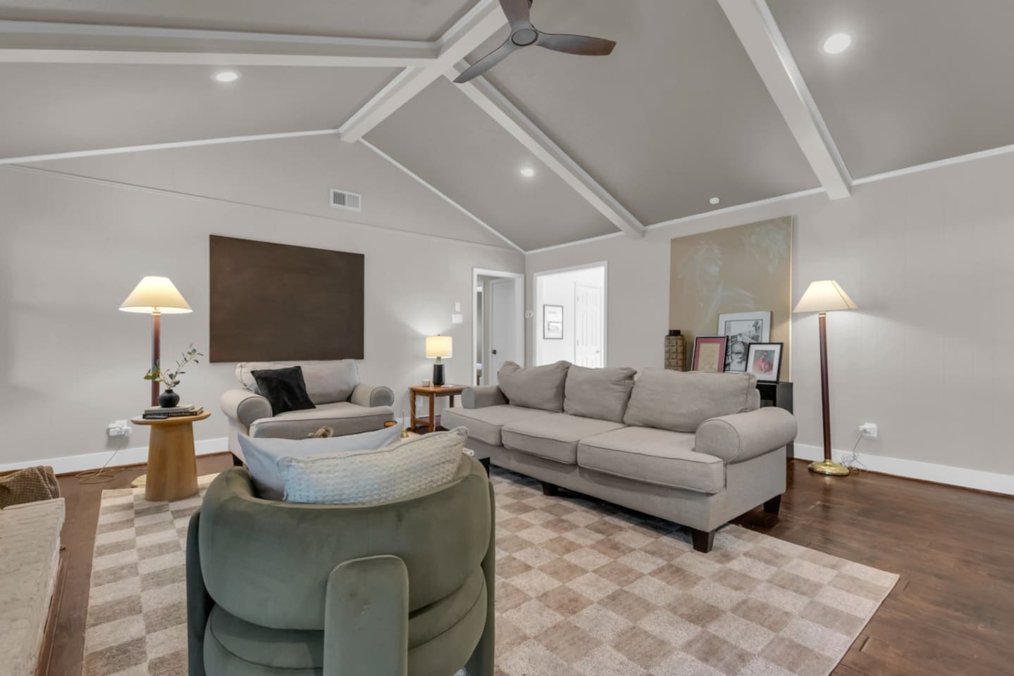 Additional view of the living room showcasing the spacious seating, artwork, and open-concept flow into the kitchen and dining area.