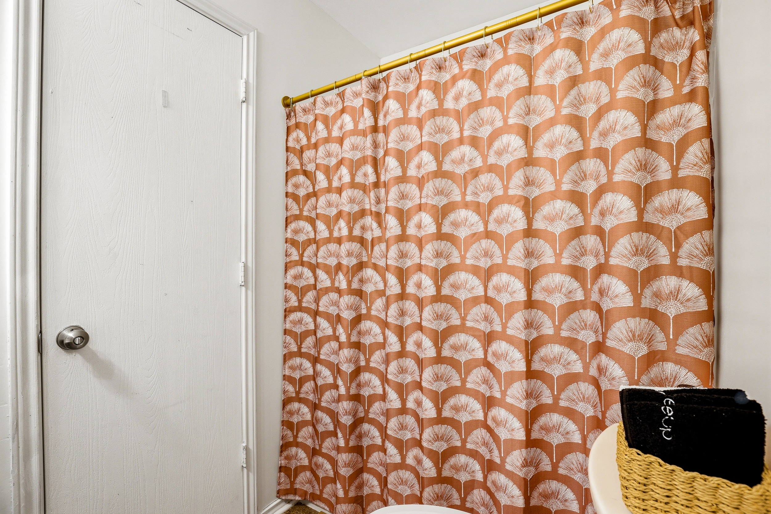 Bathroom shower and tub with gold curtain rod and bold patterned curtain — thoughtful design details carried throughout both bathrooms in this Northwest San Antonio home.