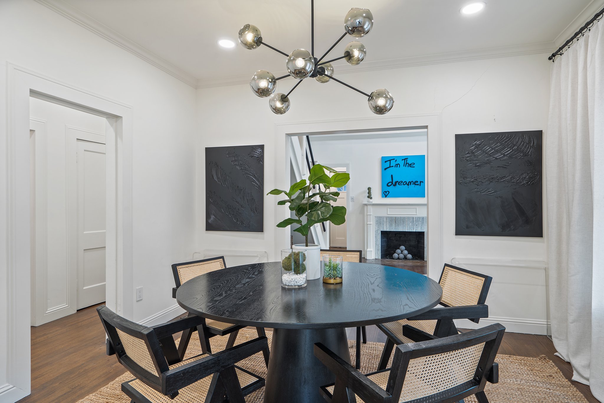 Dining area with sputnik chandelier and open-concept layout connecting to the living room and kitchen. Comfortable seating for 6 with hardwood floors and natural light throughout.