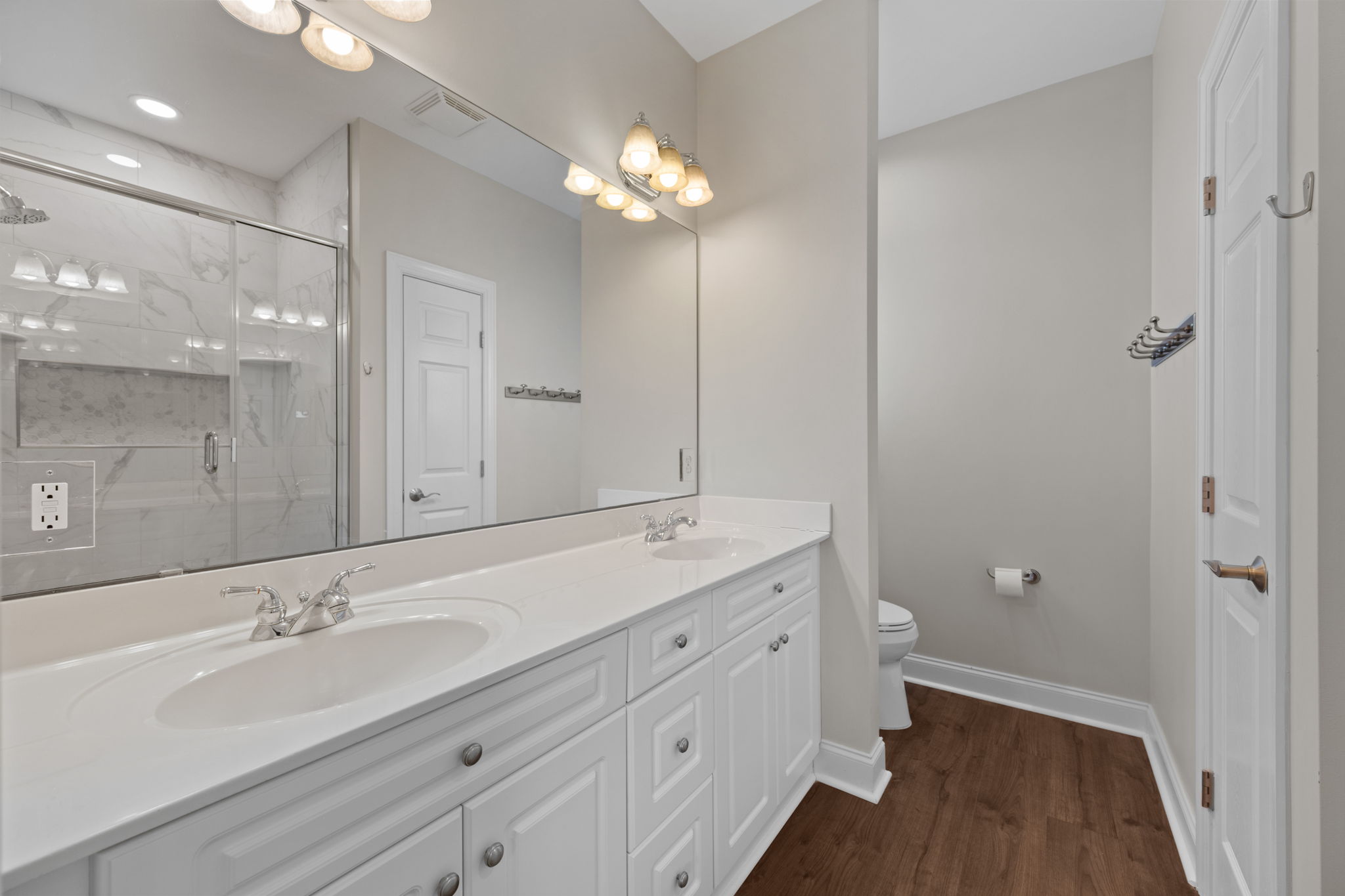 Primary bathroom featuring double sinks, luxurious shower, and a linen closet