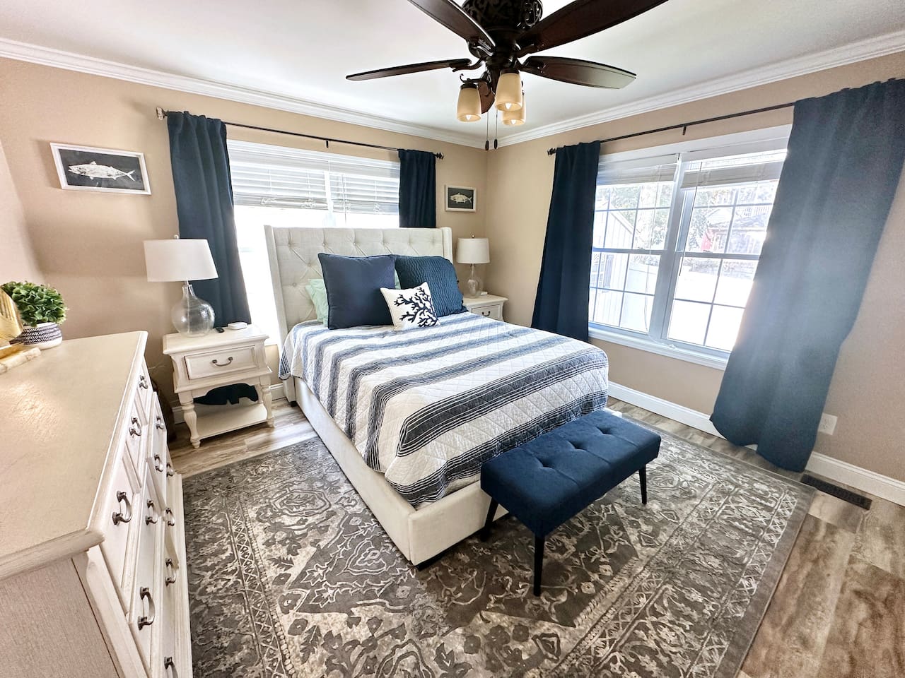 Retreat to this serene bedroom featuring a comfortable tufted bed and soft coastal accents. With dual windows providing plenty of natural light and ample storage in the large dresser, it’s a restful space designed for a great night's sleep.