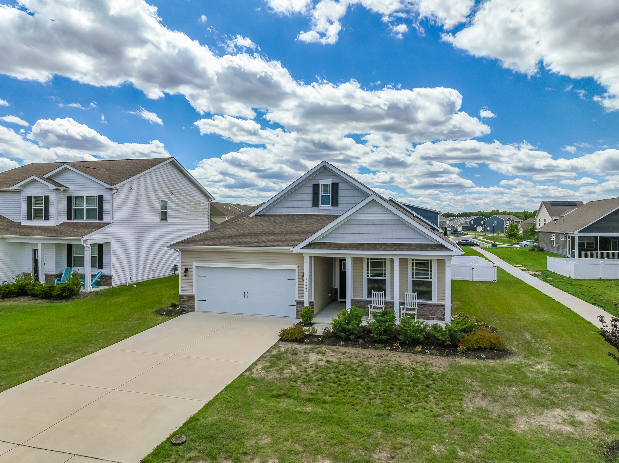 Approach via a smooth concrete driveway leading to a two-car garage, accented by manicured beds and welcoming rocking chairs on the covered front porch—your guests’ first glimpse of home comfort.