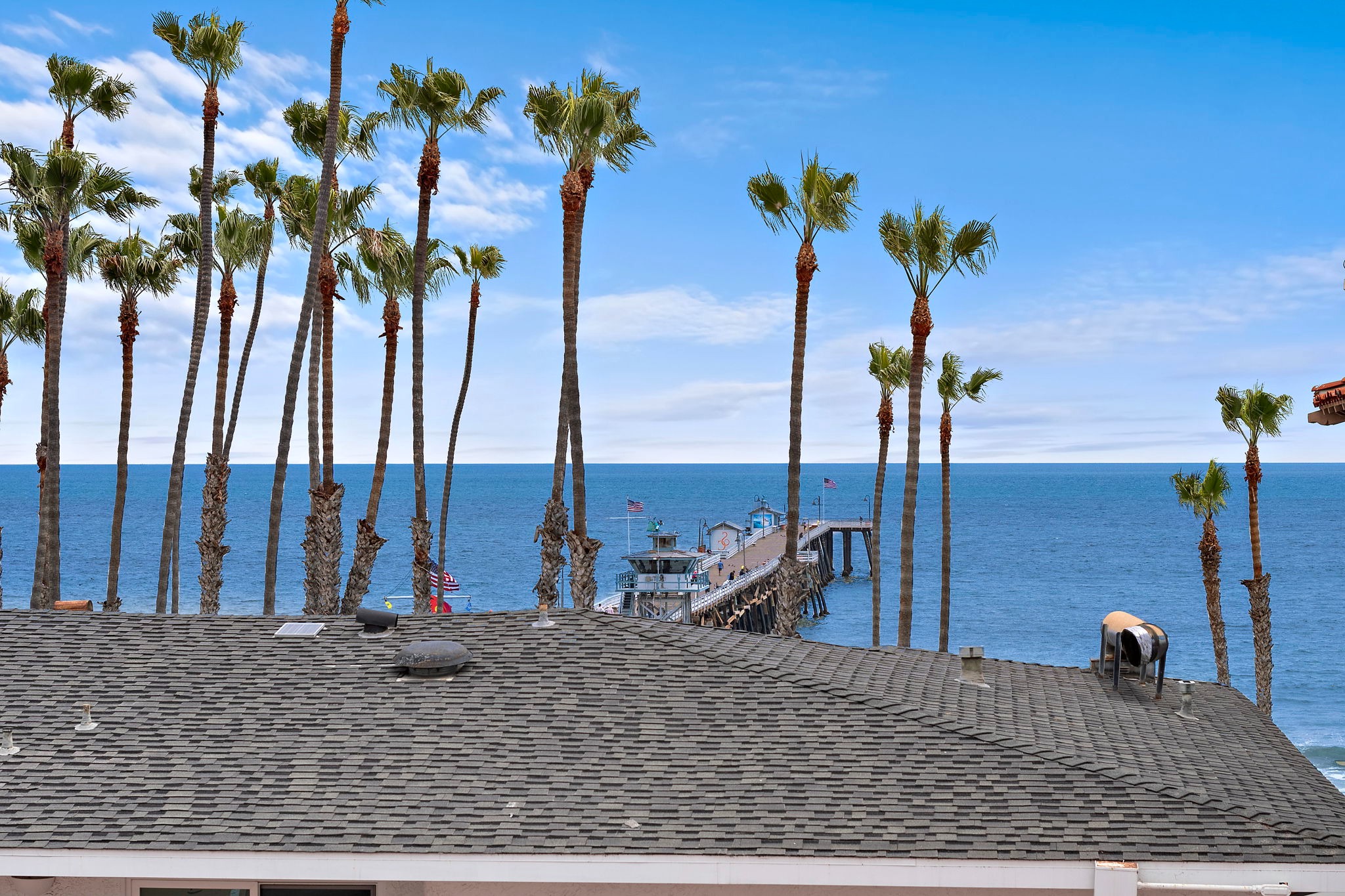 New listing from hosts with 4.99 star cumulative rating!  The view is full of palm trees and a vast horizon. Gentle ocean breezes and the sounds of waves will remind you just how close you are to the pier and the beach.