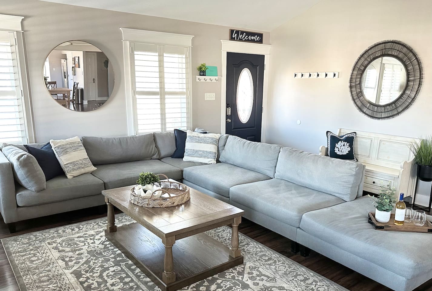 This bright entry and living area features a large, comfortable sectional perfect for group gatherings. Elegant mirrors and coastal accents create an airy feel, making it a welcoming spot to kick off your shoes after a fun day at the beach.