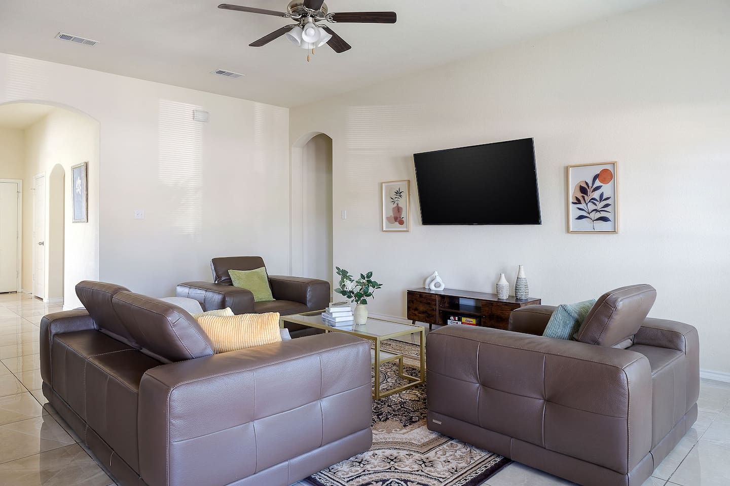 Experience the comfort of this elegant living room, featuring plush leather sofas and a large wall-mounted TV.