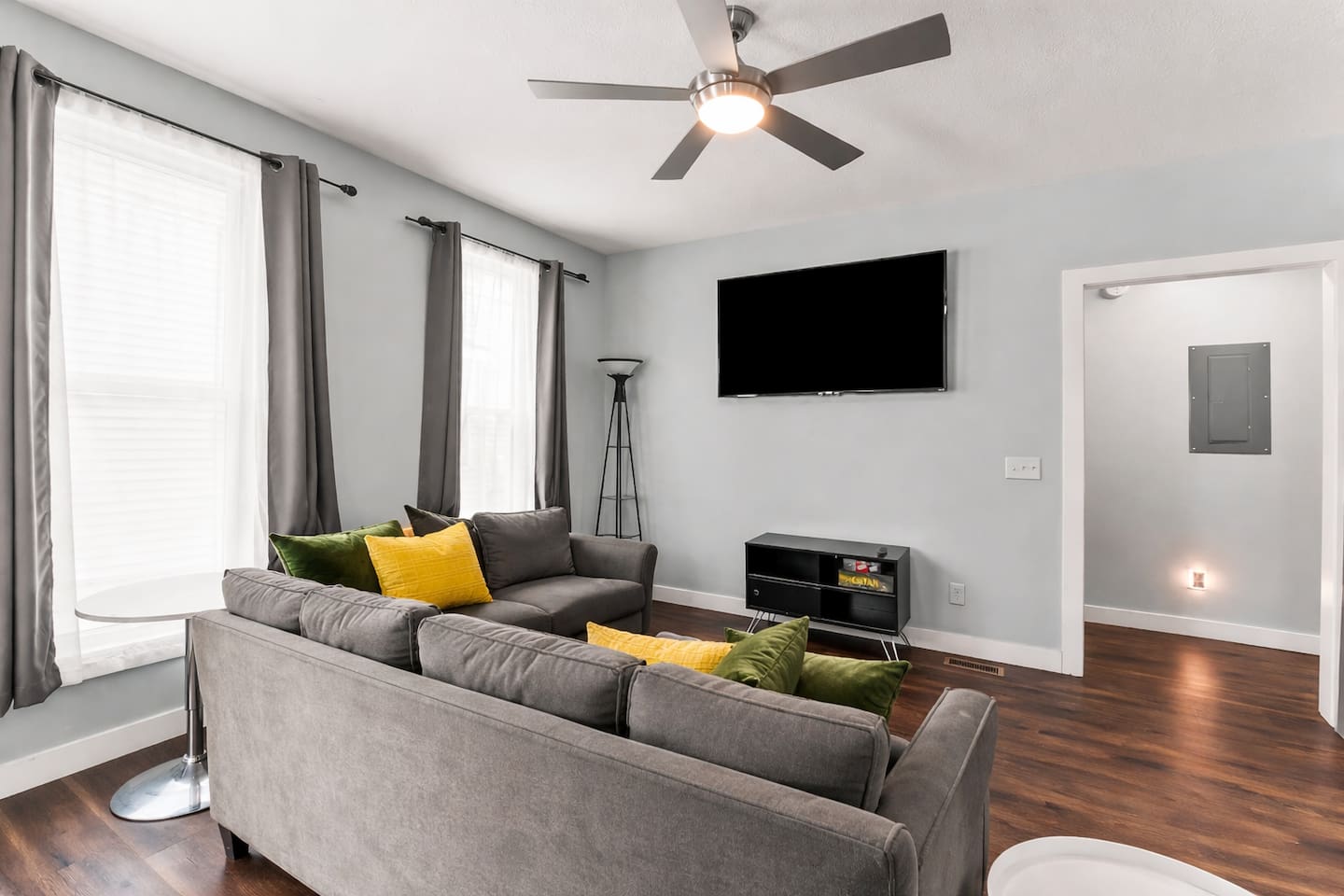 Relax in the inviting living room featuring modern lighting, hardwood floors, and a large wall-mounted TV.