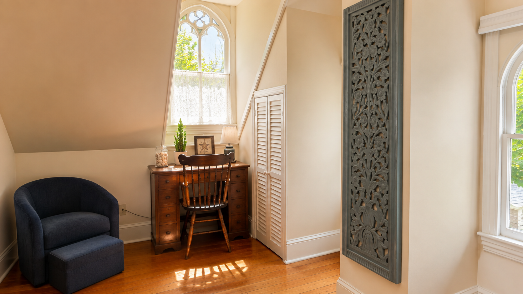 The other end of the same room — a writing desk, a reading chair, and a Gothic arch window that stops everyone who sees it. Plenty of space to spread out up here.