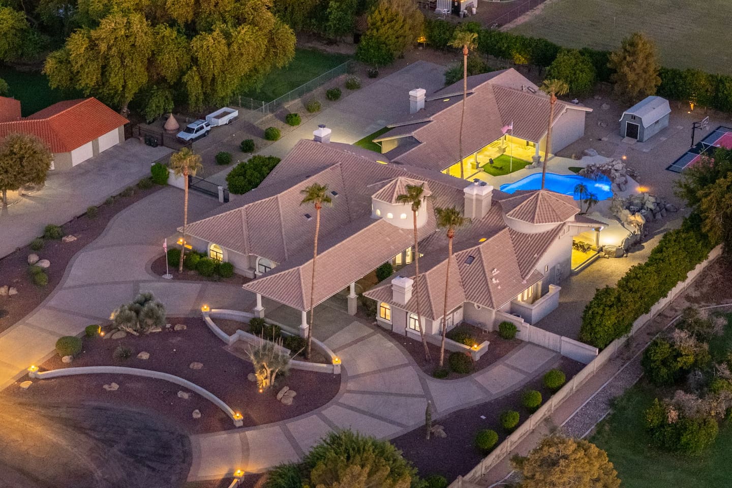 A stunning dusk shot showcasing the estate's well-lit pool, hot tub, and inviting outdoor areas.