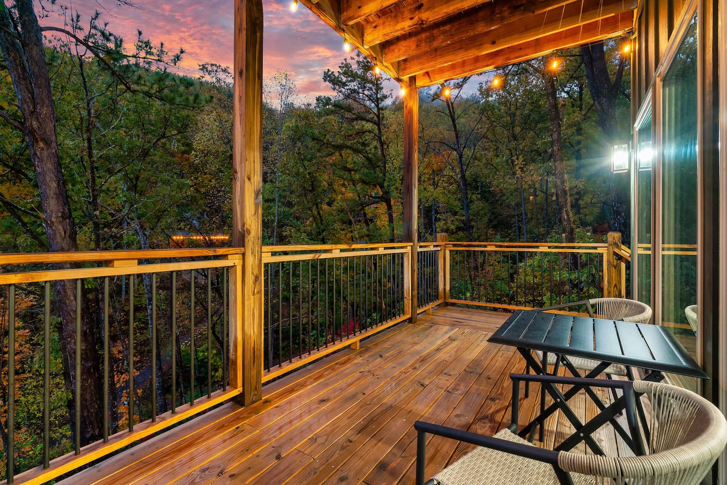 Lower-level private deck with string lights and peaceful wooded views.