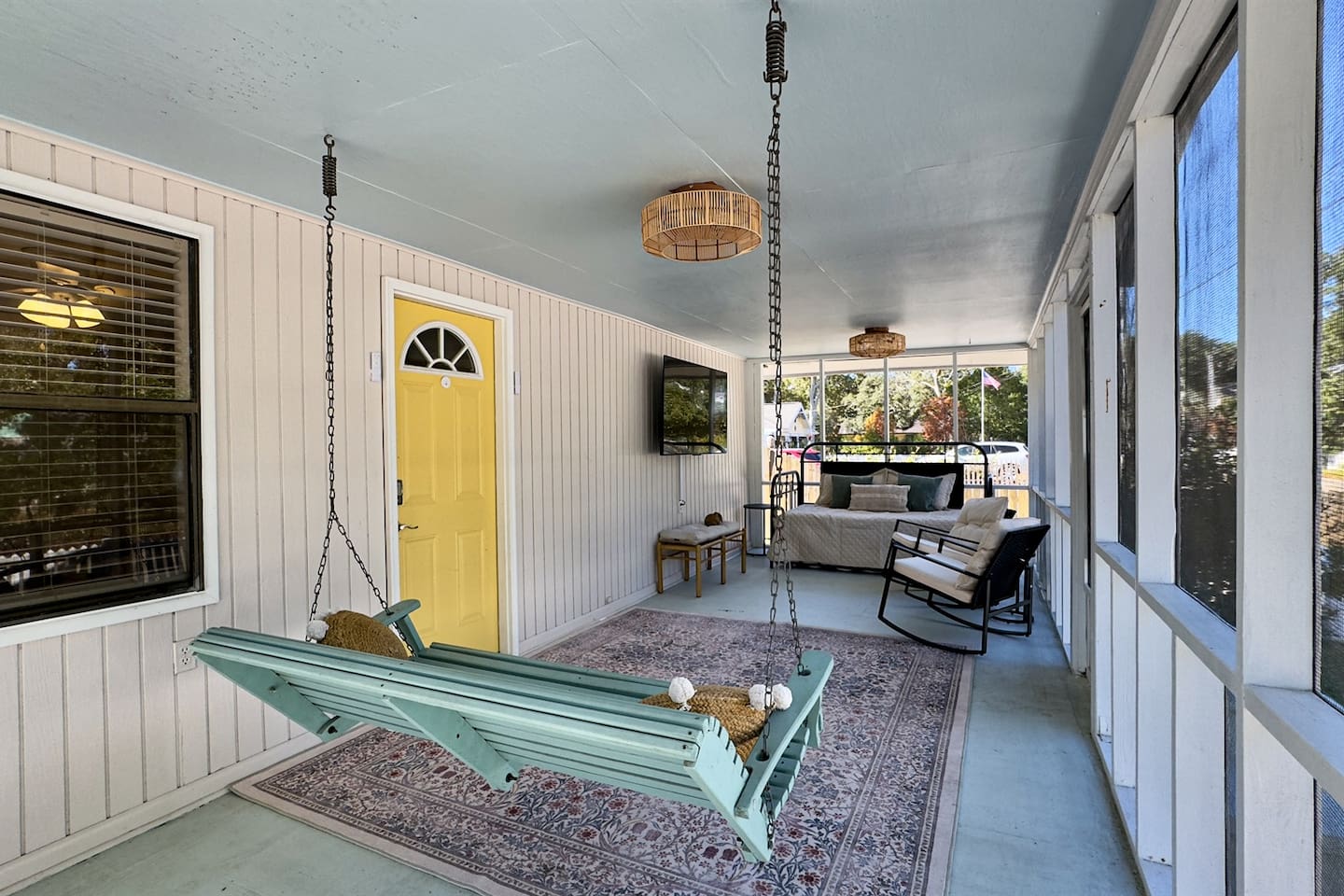Inviting screened porch with a hanging swing, cozy seating, and plenty of space to unwind outdoors.