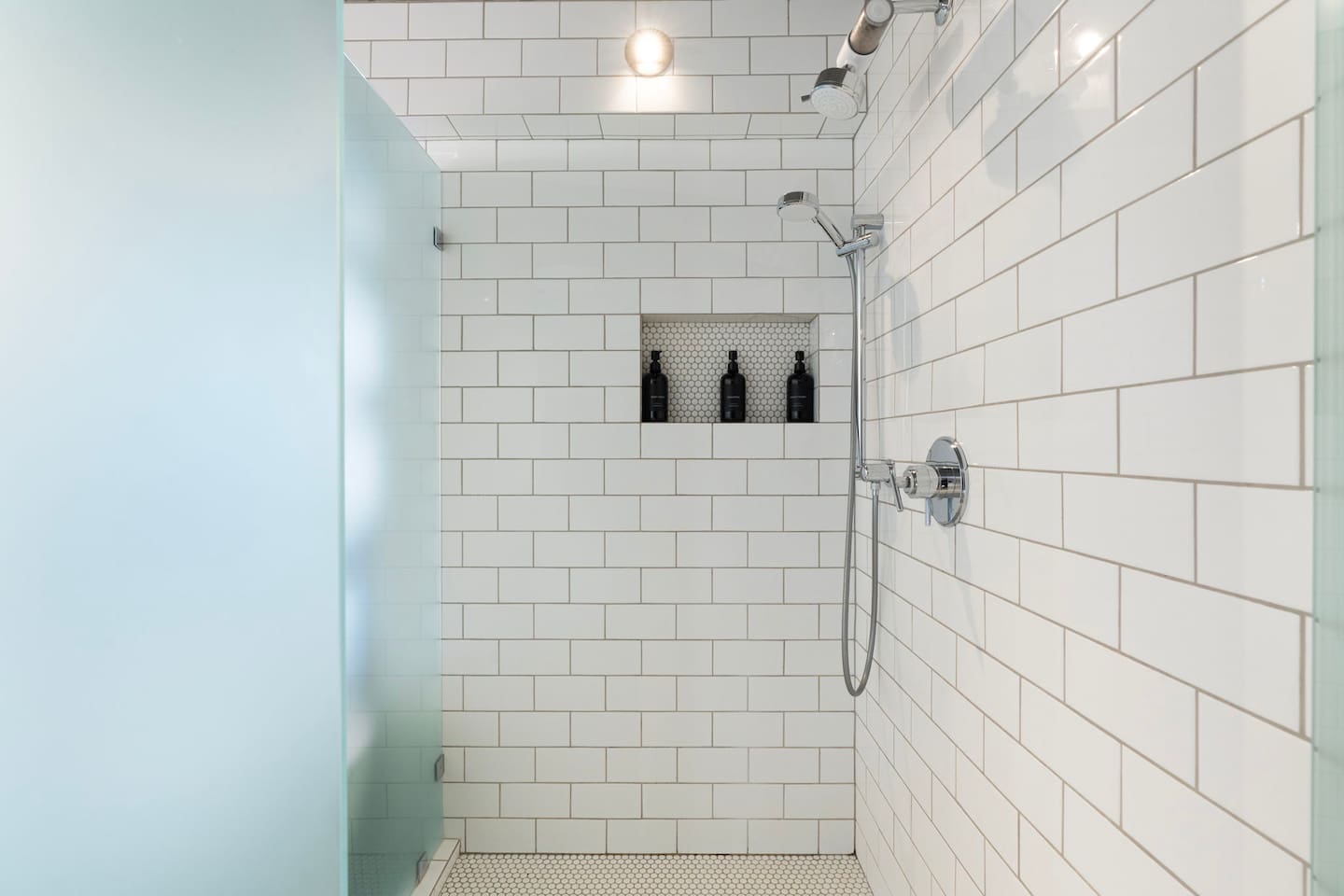 Sleek walk-in shower featuring classic white subway tile, modern chrome fixtures, and a built-in niche for added convenience — clean, bright, and beautifully designed.