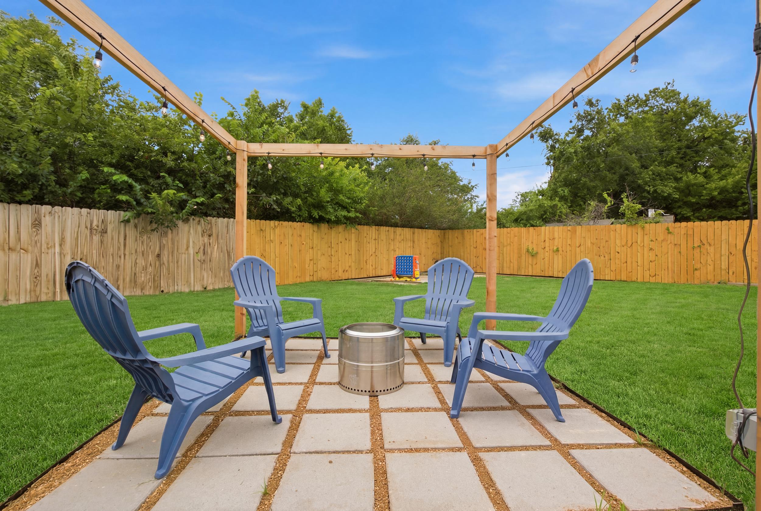 Blue Adirondack Chairs gathered around the Fire Pit under the Pergola. Cozy outdoor seating for s'mores, stargazing, and post-game recaps.
