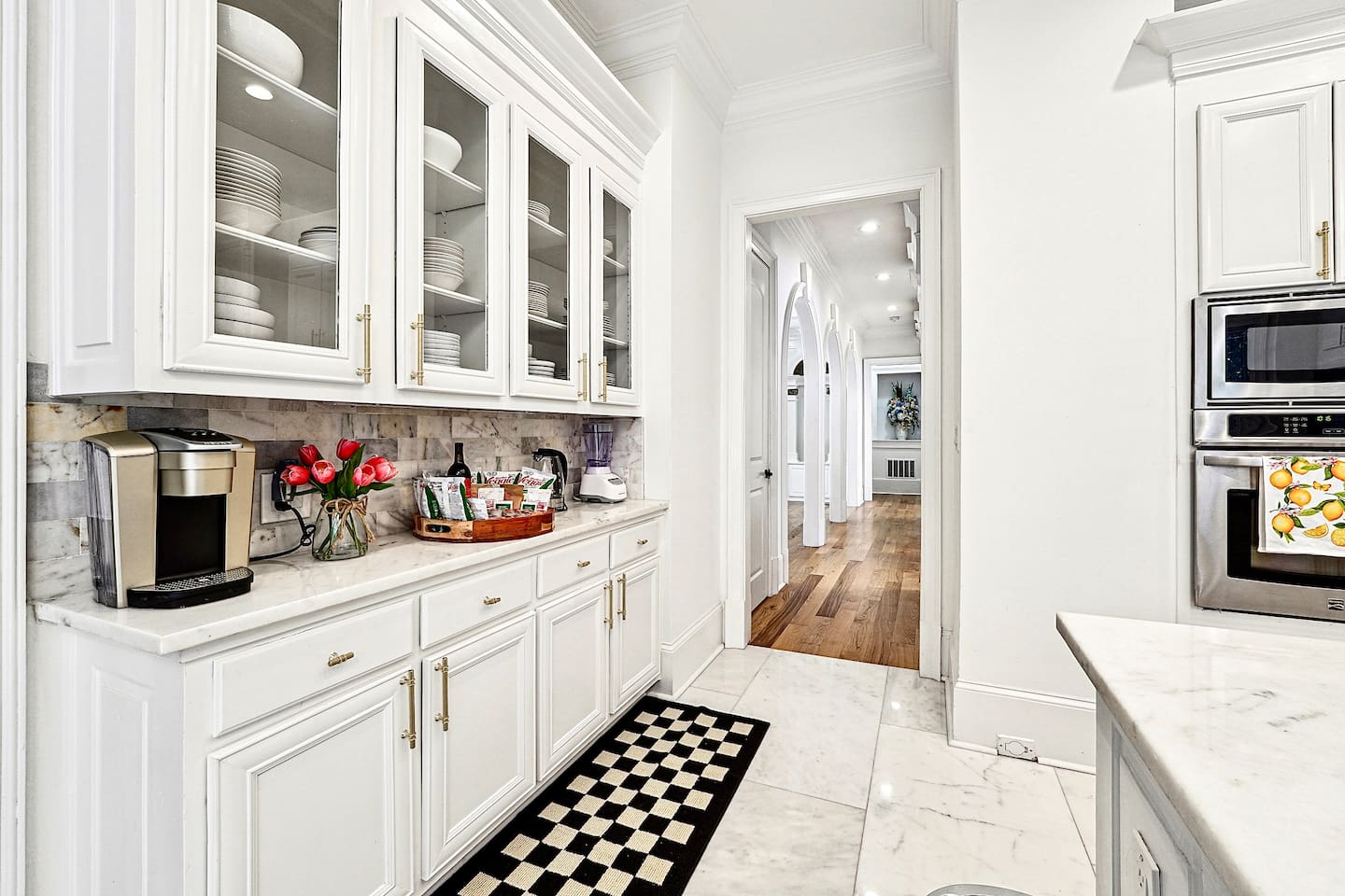 Bright and beautifully designed kitchen with white marble counters and white wood cabinetry. Fully equipped and ideal for cooking, gathering, and hosting with ease.