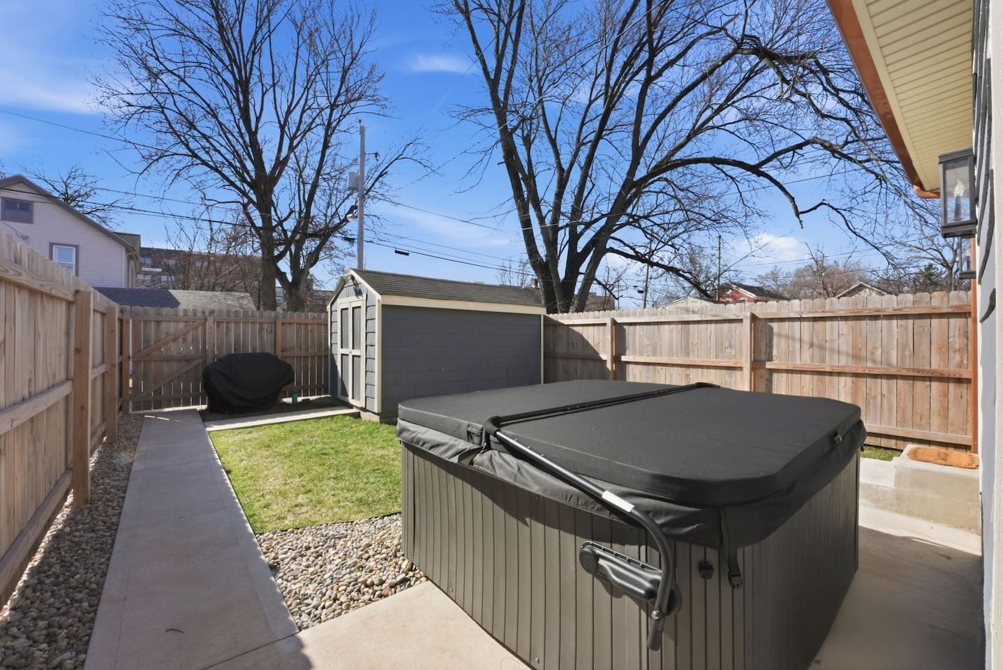 Fully fenced yard with hot tub and seating space, offering privacy and comfort
