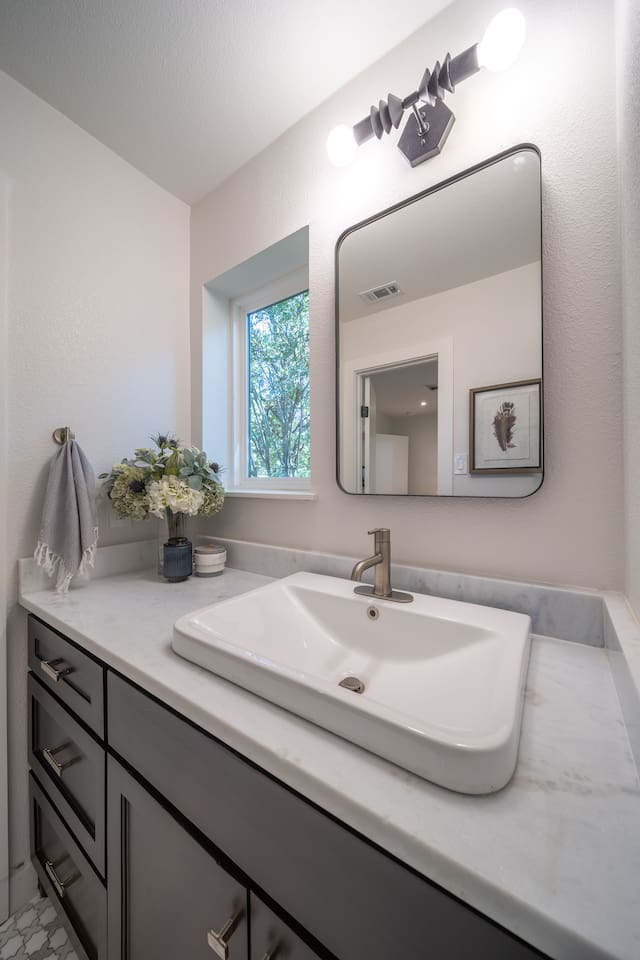 The ensuite bathroom for Bedroom 2 features a marble-topped vanity, modern fixtures, and soft lighting that enhances the clean, timeless finishes. 