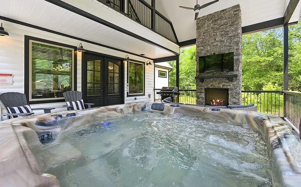 Private hot tub area with covered patio and fireplace.