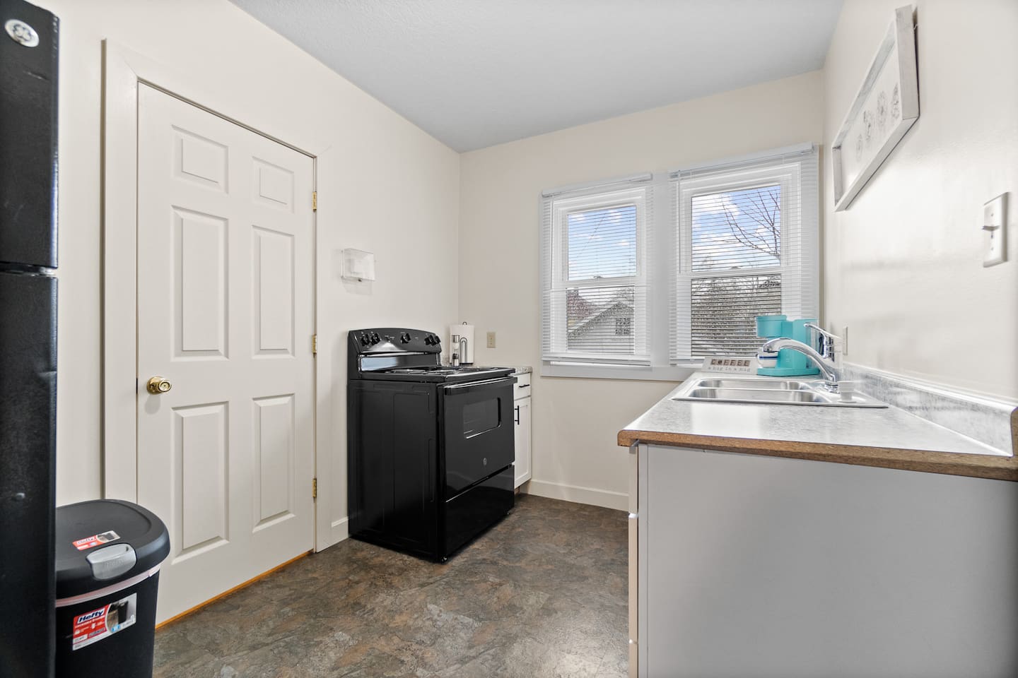 Modern full kitchen featuring a sleek sink with faucet, stylish cabinets, elegant granite countertops, a stove, and a window that lets in natural light—designed for both functionality and contemporary style, creating an inviting cooking space