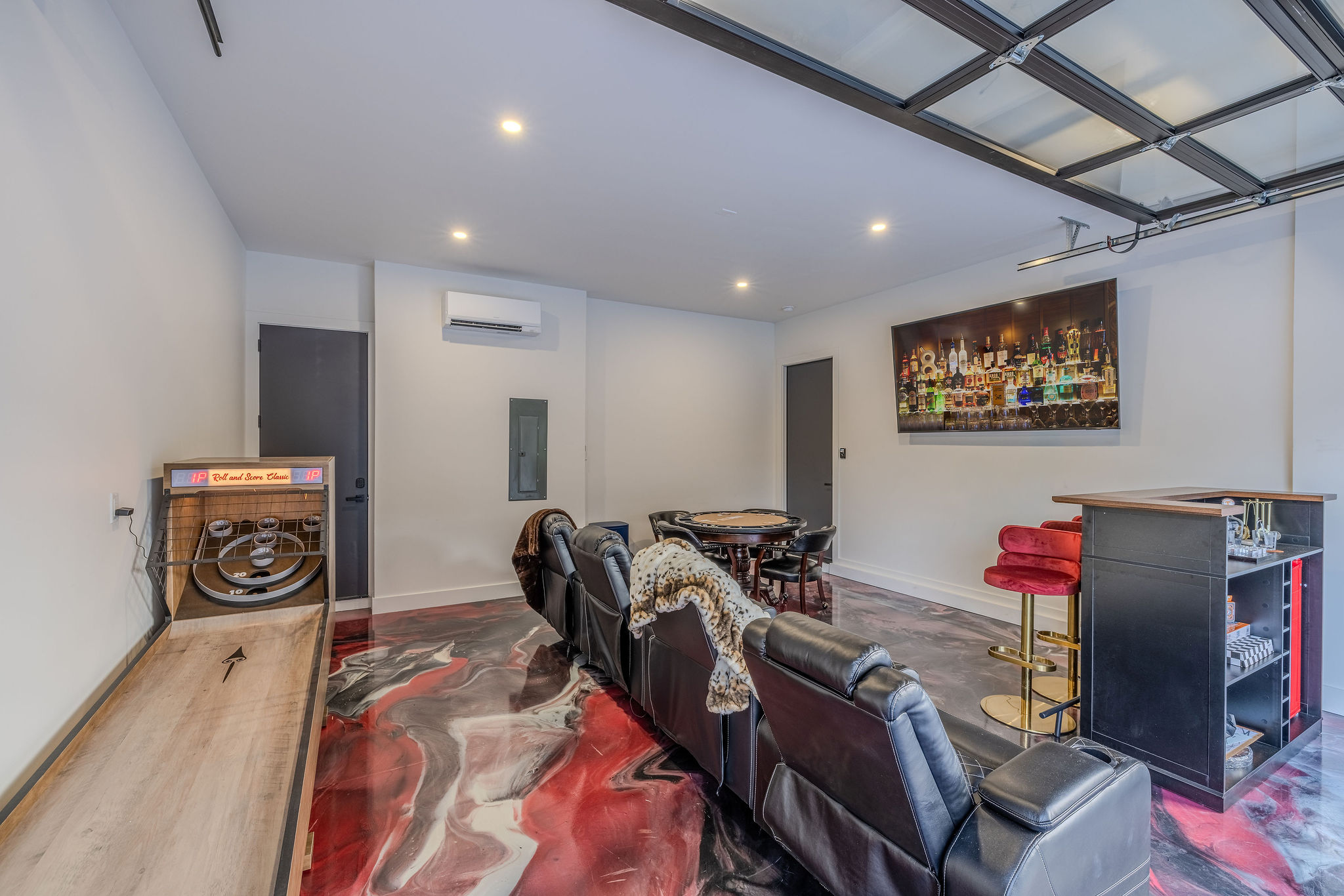 The game and theater room features skee ball, theater seating and a glossy epoxy floor.