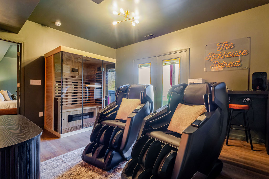 A serene pause between sauna sessions — plush towels rest within reach at the towel bar as the massage chairs deliver a deep, revitalizing release against a backdrop of artful design and calm energy.