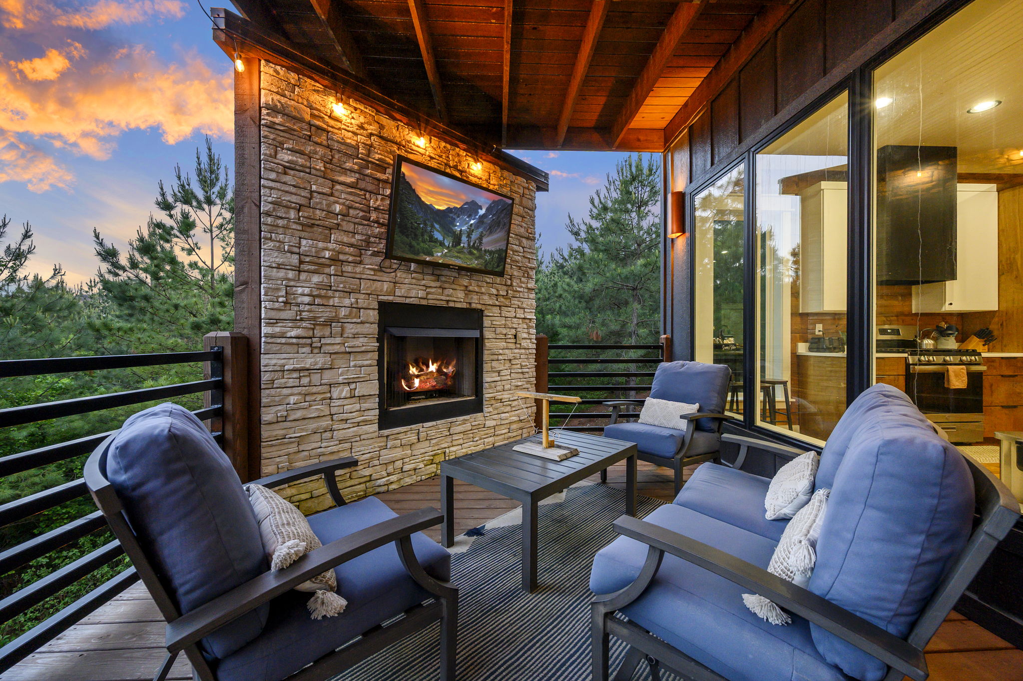 Covered patio with stone fireplace and comfortable seating—enjoy year-round outdoor living at this Broken Bow getaway.