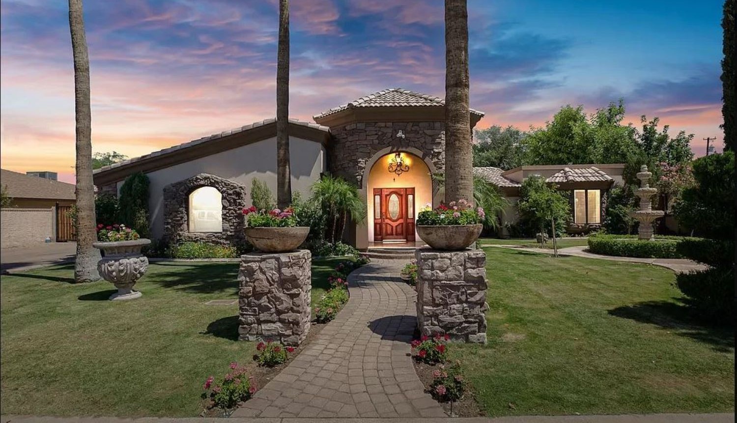 Step into your private oasis, a stone-accented haven surrounded by lush gardens, glowing sunsets, and a grand entrance that warmly welcomes you home.