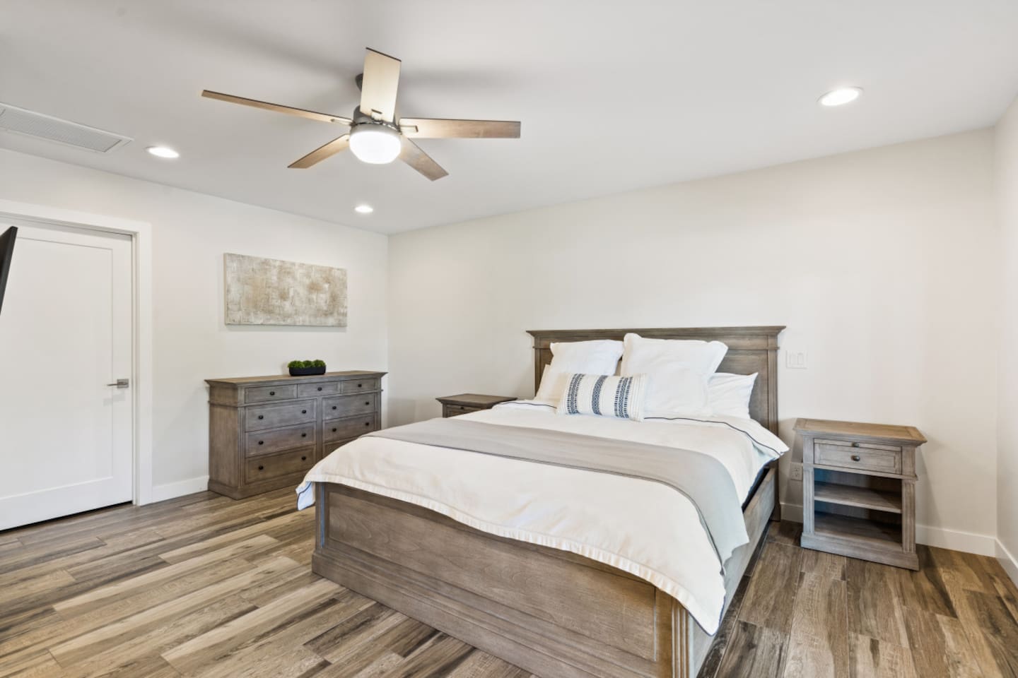 Main ensuite bedroom with queen bed, clean bedding, storage, and a simple restful layout. Master closet includes crib/baby sleeping and changing equipment.