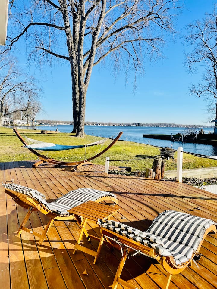 Large lakeside deck with lounge chairs overlooking the water.