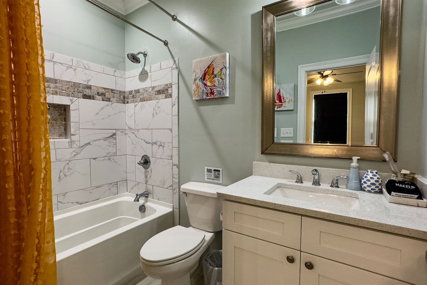 Modern bathroom with a tiled tub/shower combo, sleek vanity, and warm accent details.