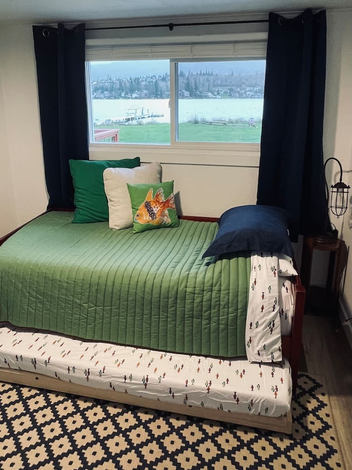 A playful room with twin and trundle beds invites imagination, where ocean creatures, moonlit adventures, and hints of camping spark curiosity and fun.