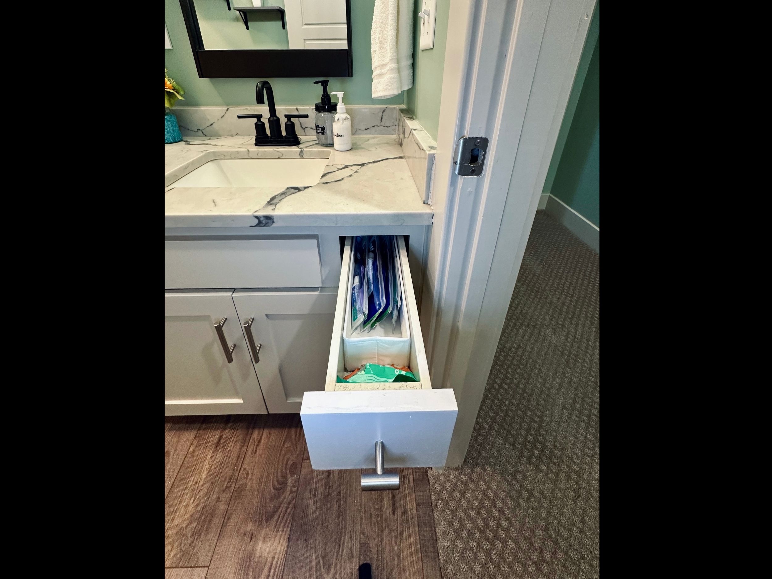Hall bathroom vanity drawer stocked with toothbrushes, toothpaste, and floss for practical daily needs.