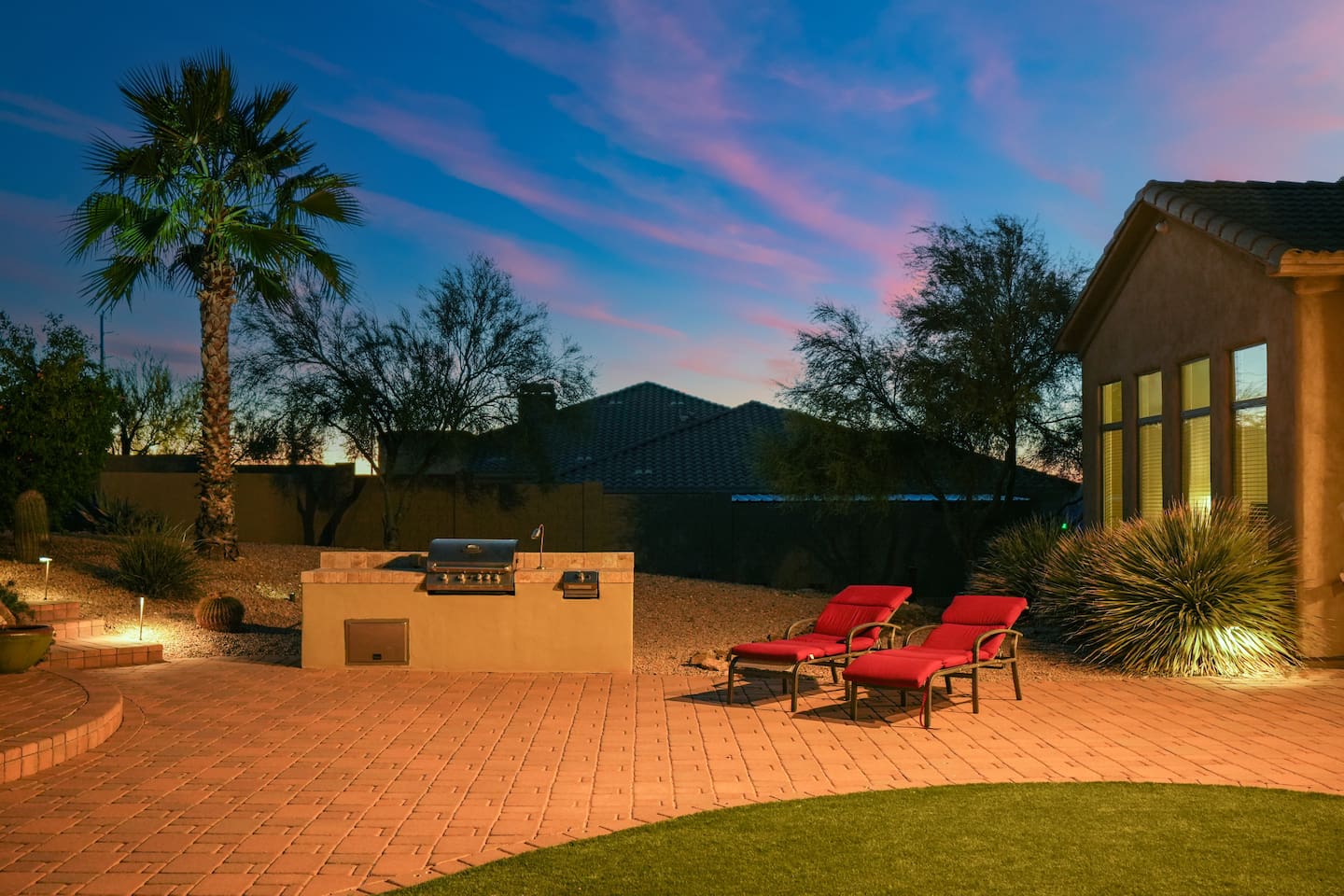 Built-in BBQ grill and lounge chairs set on a spacious patio, ideal for outdoor dining and relaxation.