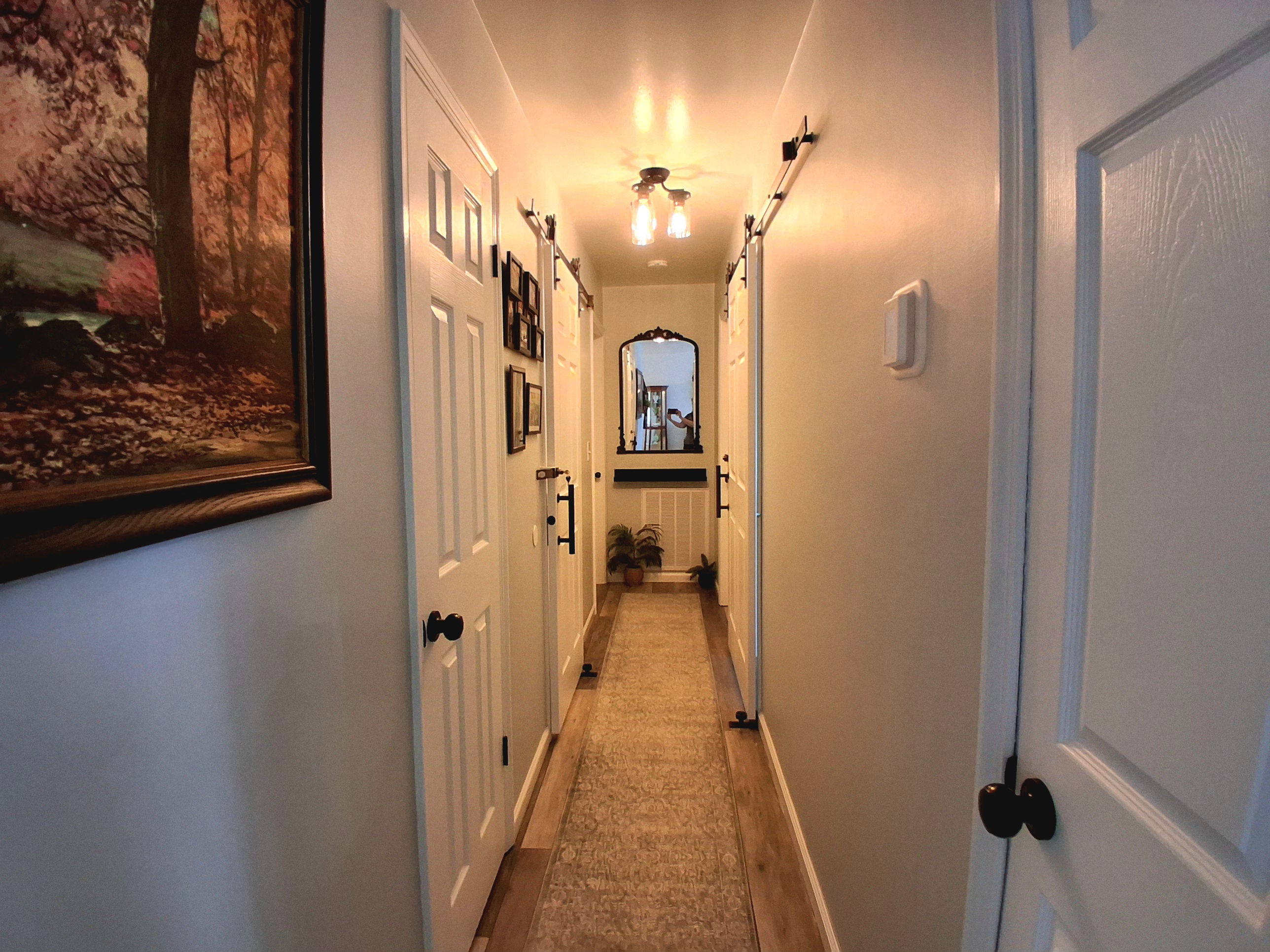 This is the hallway. Two bathrooms face each other, each equipped with sliding barn doors to optimize space. Additionally, there are two hallway closets—one housing the WiFi system and the other designated for cleaning supplies.
