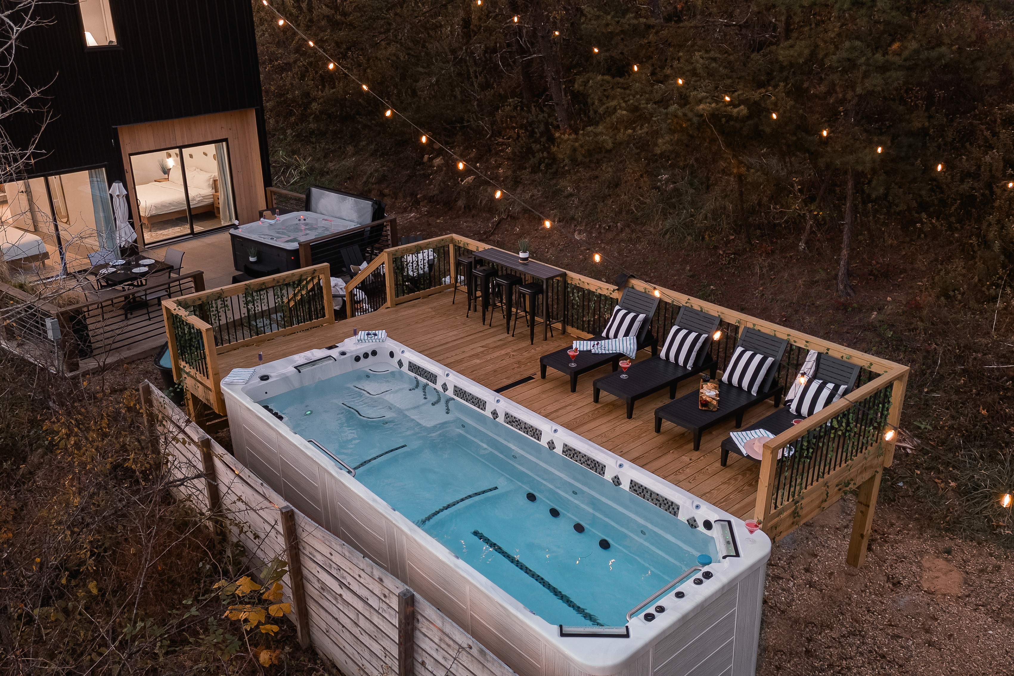 {Swim Spa Deck} Your own year-round retreat: a 21-ft heated swim spa, glowing string lights, and loungers ready for golden hour.